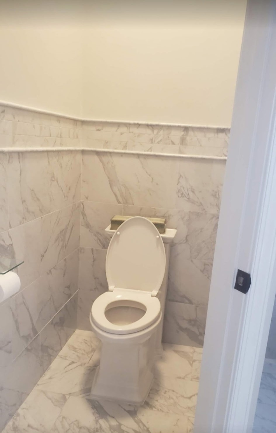 Marble tile walls and floor in a finished powder room